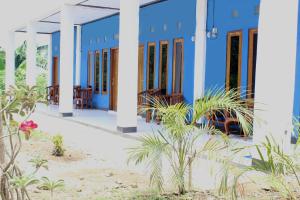 a blue and white building with plants in the foreground at Danke Lodge in Labuan Bajo
