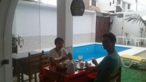 a man and woman sitting at a table near a pool at La Maison de Lydia in Nazca