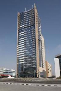 a tall building with many windows in a city at Nour Arjaan by Rotana-Fujairah in Fujairah