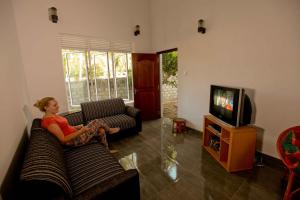 a woman sitting on a couch watching tv in a living room at HOSTEL KATUNAYAKE At COLOMBO AIRPORT TRANSIT in Katunayake
