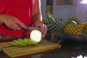 a woman cutting an apple on a cutting board with a knife at HOSTEL KATUNAYAKE At COLOMBO AIRPORT TRANSIT in Katunayake
