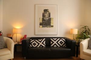 sala de estar con sofá negro y 2 sillas en B&B Belgravia, en Londres