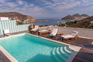 a swimming pool with chairs and a view of the ocean at Theologos Houses in Grikos