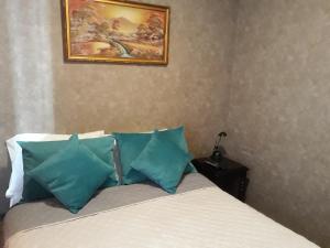 a bed with blue pillows and a painting on the wall at Apartment 209 in Santiago