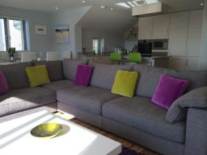 uma sala de estar com um sofá com almofadas roxas e amarelas em 9 Sandpiper Cottages em Newquay