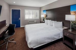 a bedroom with a large bed with a desk and a blue door at Vallejo Inn in Vallejo