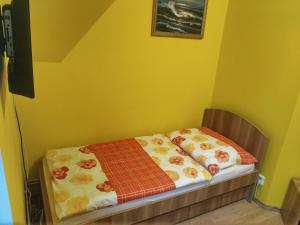 a bed in a room with a yellow wall at Penzion U Krejzů in Dolní Poustevna