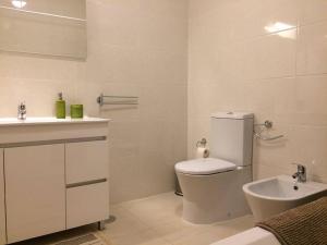 bagno bianco con servizi igienici e lavandino di apartamento a Porto
