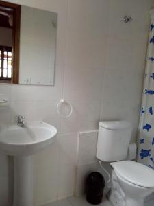 a white bathroom with a toilet and a sink at Chalés Ubatubaloft in Ubatuba