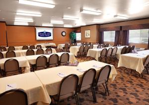 a conference room with tables and chairs and a screen at Crystal Inn Hotel & Suites - Midvalley in Murray