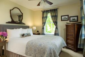 Squam Lake Inn في Holderness: غرفة نوم بسرير ومرآة ونافذة