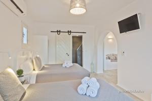 a white bedroom with two beds and a tv at Lux View Villas in Kyra Panagia