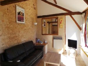 a living room with a black couch and a tv at Les Coustilles in Saint-Alvère