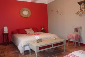 een rode slaapkamer met een bed en een tafel bij gîte de la Domergue in Mas-Saintes-Puelles