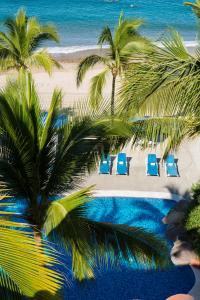 uma vista aérea de uma praia com cadeiras e palmeiras em Hotel El Pescador em Puerto Vallarta