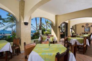 a restaurant with tables and chairs with the ocean in the background at Hotel El Pescador in Puerto Vallarta