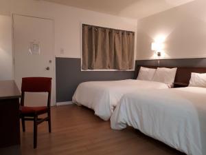 una camera d'albergo con due letti, una scrivania e una sedia di Falcon Nest Motel a Duncan