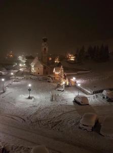 eine schneebedeckte Stadt in der Nacht mit einer Kirche in der Unterkunft Ciasa Gabriel in Kolfuschg