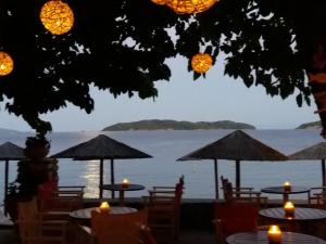 a view of the water from a restaurant with tables and umbrellas at Maniatis Garden in Achladies