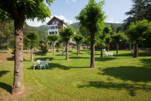 a park with tables and chairs and a building at Hostal Les Fonts in Castellar de NʼHug