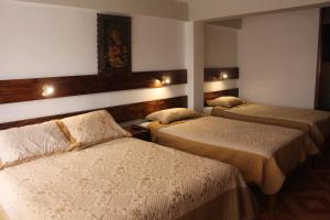 1 dormitorio con 2 camas y luces en la pared en Kennedy Guest House, en Cusco