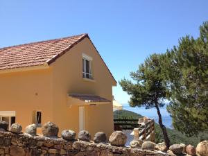 une maison avec une clôture en pierre et un arbre dans l'établissement Villa Romarin, à Partinello