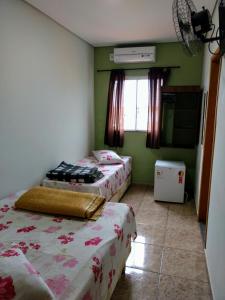 two beds in a room with green walls and a window at Hotel Jardim Paraiba in Aparecida