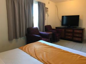 a hotel room with a bed and a flat screen tv at Hotel Guillen Jr in Tijuana