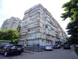 a tall building with cars parked in front of it at Comfortable isolated turnkey room near the subway and the International Exhibition Center in Kyiv