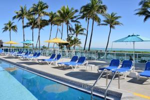 una fila de sillas y sombrillas junto a una piscina en Seacoast Suites on Miami Beach en Miami Beach