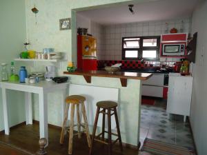 una cocina con barra y dos taburetes. en Santinho Hostel, en Florianópolis