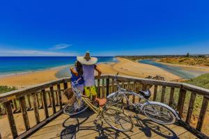 a person on a bike next to a beach at Coast Motel and Apartments in Port Noarlunga