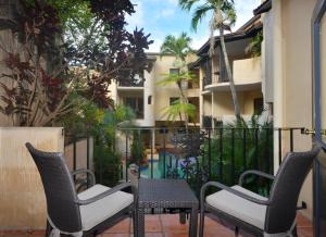 two chairs and a table on a balcony with a building at Seascape Apartments at Villa San Michele in Port Douglas
