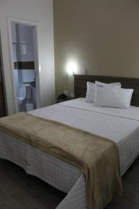 ein Schlafzimmer mit einem großen Bett mit weißer Bettwäsche und Kissen in der Unterkunft Hotel Infinity in Mauá