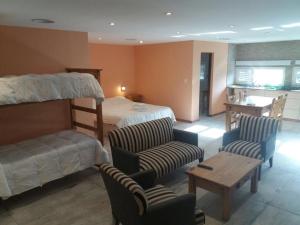 a bedroom with a bunk bed and chairs and a table at Calafate Hostel in El Calafate