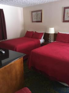 two beds in a hotel room with red sheets at Anchor Motel in Niagara Falls