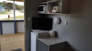 a living room with a tv and a microwave at Scamander Tourist Park in Scamander