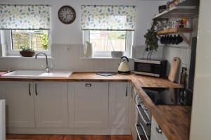 a kitchen with white cabinets and a wooden counter top at Foxglove Cottage in Clearwell