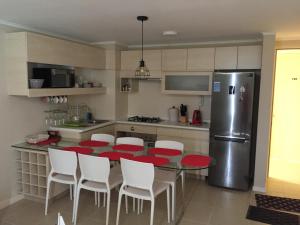 cocina con mesa, sillas blancas y nevera en Laguna Bahia 711 Algarrobo, en Algarrobo