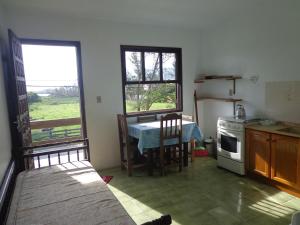cocina con mesa, fogones y ventana en Apartamento Sul na Praia da Ferrugem, en Garopaba