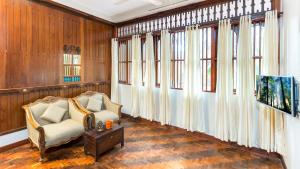 a living room with a chair and windows at Kumarakom Wood Castle Serviced Appartments in Kumarakom