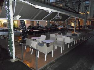 un restaurante con mesas blancas y sillas en una calle de la ciudad en Senka, en Zagreb