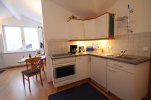 een keuken met witte kasten, een wastafel en een tafel bij Ferienwohnung Sabrina in Oberstaufen