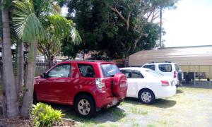 a red car parked in front of a white house at Sail Inn Motel in Yeppoon