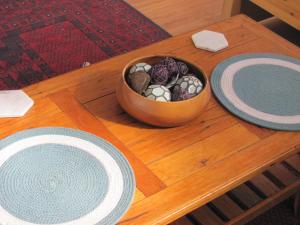 a wooden table with a bowl of rocks and two plates at Bower's Hideout in Kandos