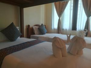 dois elefantes de peluche sentados em cima de duas camas em Baan Bussaba Hotel em Trang
