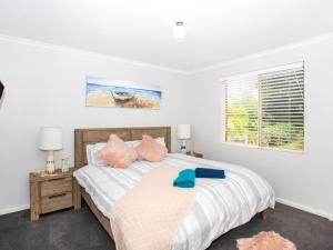 a bedroom with a bed with pink pillows and a window at Fairway Haven Getaway in Mollymook