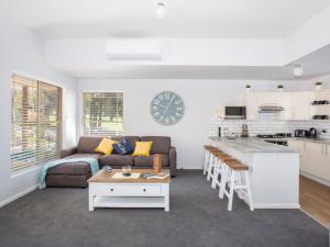 ein Wohnzimmer mit einem Sofa und einem Tisch sowie eine Küche in der Unterkunft Fairway Haven Getaway in Mollymook