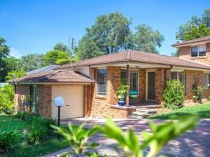 a brick house with a garage in a yard at Fairway Haven Getaway in Mollymook
