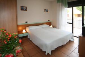 sypialnia z białym łóżkiem i oknem w obiekcie Hotel Etna w Lignano Sabbiadoro